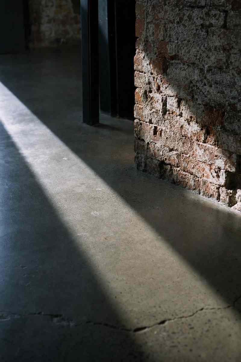 Een streep licht over een betonvloer langs een bakstenen muur