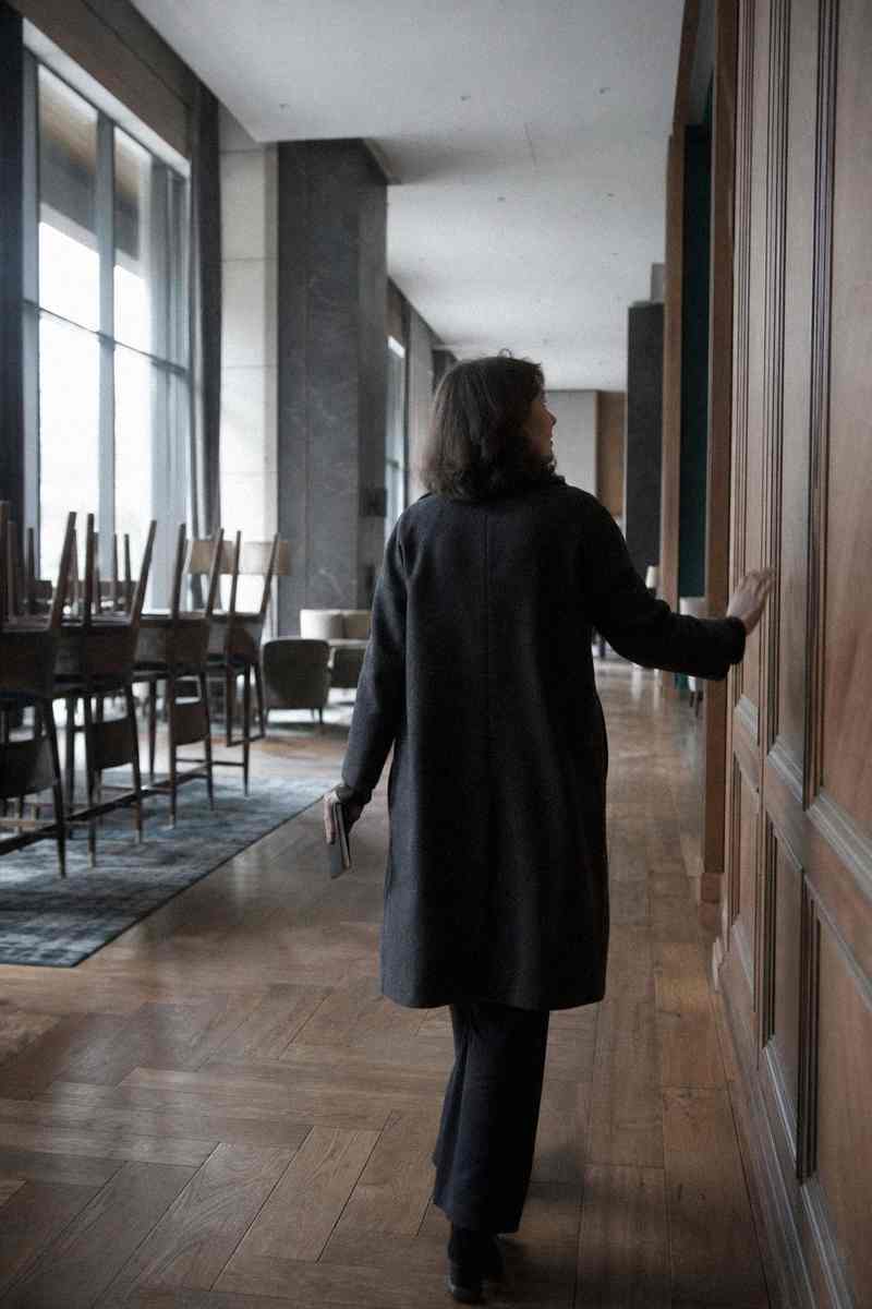 Iemand loopt door een lange gang met houten wanden en raakt de wand aan