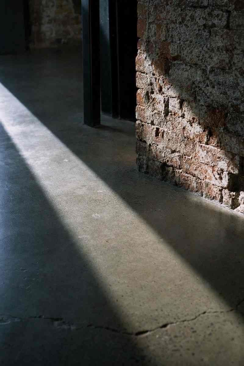 Een streep licht over een betonvloer langs een bakstenen muur